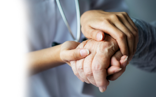 Mão de médica segurando mão de paciente idoso