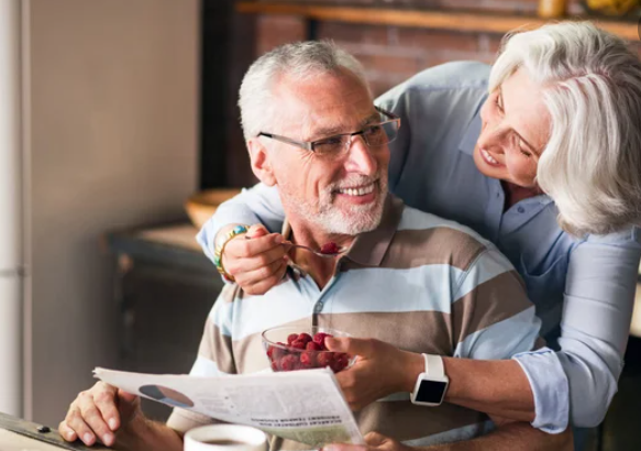 Casal de idosos se olhando e comendo fruta - prevenção de doença 